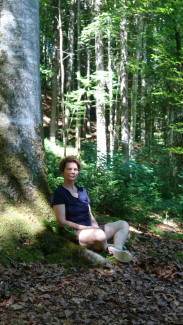 Frau sitzt unter einem Baum im Wald